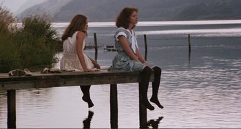 Movie still from “Julia” (1977), directed by Fred Zinnemann – Two women sitting on a dock by a body of water; Wide shot, Low angle