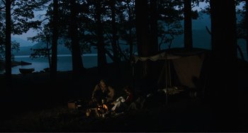 Movie still from “Julia” (1977), directed by Fred Zinnemann – A couple of people sitting around a fire in the dark; Extreme Wide shot, High angle