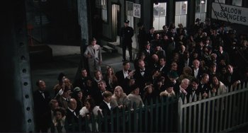 Movie still from “Julia” (1977), directed by Fred Zinnemann – A crowd of people sitting in front of a picket fence; Wide shot, High angle