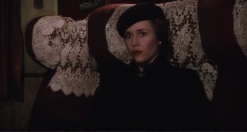Movie still from “Julia” (1977), directed by Fred Zinnemann – A woman wearing a hat sitting on a couch; Medium shot, High angle