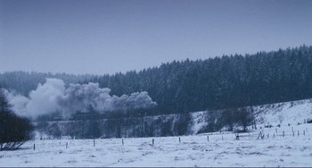 Movie still from “Julia” (1977), directed by Fred Zinnemann – Smoke billows out of a train on a snowy day; Extreme Wide shot, Low angle
