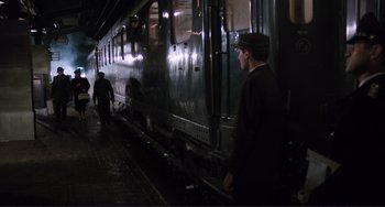 Movie still from “Julia” (1977), directed by Fred Zinnemann – A man standing next to a train on a train track; Wide shot, High angle