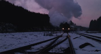 Movie still from “Julia” (1977), directed by Fred Zinnemann – A train traveling down train tracks near a forest; Extreme Wide shot, Low angle