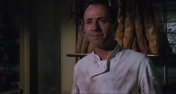 Movie still from “Julia” (1977), directed by Fred Zinnemann – A man in a chef's outfit standing in front of a curtain; Close Up shot, Low angle
