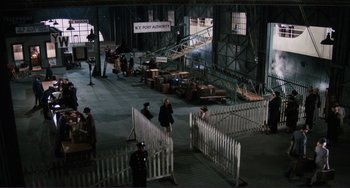 Movie still from “Julia” (1977), directed by Fred Zinnemann – A group of people standing in a building with white fences; Extreme Wide shot, High angle