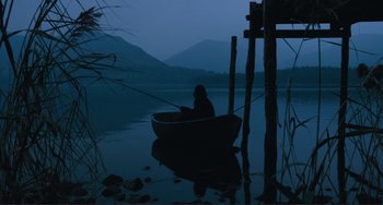 Movie still from “Julia” (1977), directed by Fred Zinnemann – A person sitting in a boat on a body of water at night; Extreme Wide shot, High angle