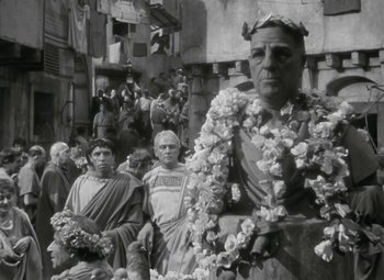Movie still from “Julius Caesar” (1953), directed by Joseph L. Mankiewicz – An old photo of a crowd of people with flowers in their hair; Medium shot, Low angle