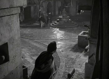 Movie still from “Julius Caesar” (1953), directed by Joseph L. Mankiewicz – A man walking through a courtyard with a fountain; Extreme Wide shot, High angle