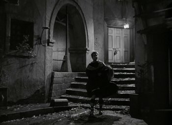 Movie still from “Julius Caesar” (1953), directed by Joseph L. Mankiewicz – A man sitting on some steps in a dark place; Wide shot, High angle
