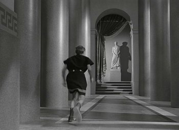 Movie still from “Julius Caesar” (1953), directed by Joseph L. Mankiewicz – A woman walking down a hall way with columns and a statue; Wide shot, Low angle