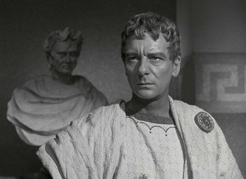 Movie still from “Julius Caesar” (1953), directed by Joseph L. Mankiewicz – A man in a roman outfit standing in front of a statue; Close Up shot, Low angle