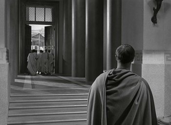 Movie still from “Julius Caesar” (1953), directed by Joseph L. Mankiewicz – A man wearing a robe and standing in front of a building; Wide shot, Over the shoulder angle