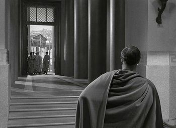 Movie still from “Julius Caesar” (1953), directed by Joseph L. Mankiewicz – A man wearing a robe and sitting on some steps; Wide shot, Over the shoulder angle