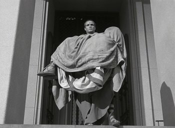 Movie still from “Julius Caesar” (1953), directed by Joseph L. Mankiewicz – A man standing in a doorway with a blanket draped over him; Wide shot, Low angle