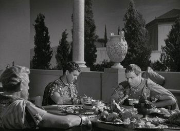 Movie still from “Julius Caesar” (1953), directed by Joseph L. Mankiewicz – A black and white photo of people sitting at a table eating food; Medium shot, High angle