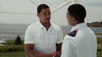 Two men shake hands in front of the ocean