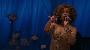 Movie still from “Jumping the Broom” (2011), directed by Salim Akil – A woman in a gold dress singing into a microphone; Medium shot, Over the shoulder angle
