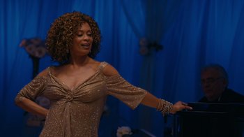 Movie still from “Jumping the Broom” (2011), directed by Salim Akil – A woman with curly hair is singing in front of a blue curtain; Medium shot, High angle