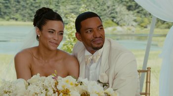 Movie still from “Jumping the Broom” (2011), directed by Salim Akil – A man and a woman sitting next to each other in front of flowers; Close Up shot, High angle