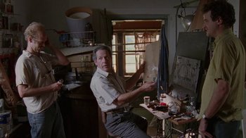 Movie still from “Junebug” (2005), directed by Phil Morrison – An older man sitting in front of an easel in a room; Medium shot, Low angle