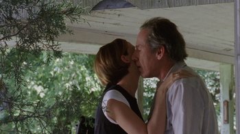 Movie still from “Junebug” (2005), directed by Phil Morrison – A man and a woman kissing in front of trees; Medium shot, Low angle