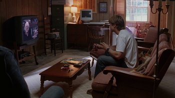 Movie still from “Junebug” (2005), directed by Phil Morrison – A man sitting in a living room playing a video game; Wide shot, High angle