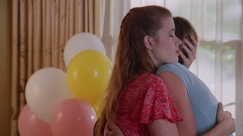 Movie still from “Junebug” (2005), directed by Phil Morrison – Two young women are hugging in front of balloons; Medium shot, Over the shoulder angle