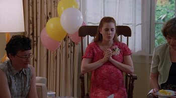 Movie still from “Junebug” (2005), directed by Phil Morrison – A pregnant woman sitting in a rocking chair with her hands clasped together; Medium shot, High angle