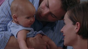 Movie still from “Junebug” (2005), directed by Phil Morrison – A man and a woman holding a baby in his arms; Close Up shot, High angle