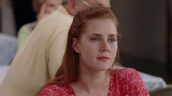 Movie still from “Junebug” (2005), directed by Phil Morrison – A woman with red hair sitting in front of other people; Close Up shot, Over the shoulder angle