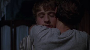 Movie still from “Junebug” (2005), directed by Phil Morrison – Two men hugging each other in a dark room; Close Up shot, Over the shoulder angle