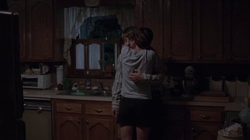Movie still from “Junebug” (2005), directed by Phil Morrison – Two people in a kitchen hugging in the dark; Medium shot, Over the shoulder angle