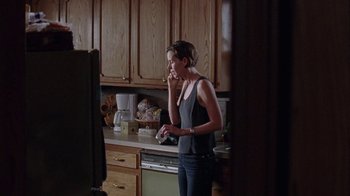 Movie still from “Junebug” (2005), directed by Phil Morrison – A woman standing in a kitchen talking on a phone; Medium shot, Over the shoulder angle