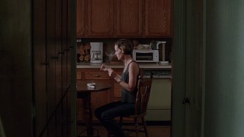 Movie still from “Junebug” (2005), directed by Phil Morrison – A woman sitting at a table in a kitchen; Wide shot, High angle