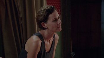 Movie still from “Junebug” (2005), directed by Phil Morrison – A woman with short brown hair sitting in front of a curtain; Close Up shot, Over the shoulder angle