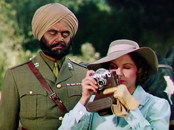Movie still from “The Jungle Book” (1942), directed by Zoltan Korda – A woman taking a picture of a man in a uniform; Medium shot, Low angle