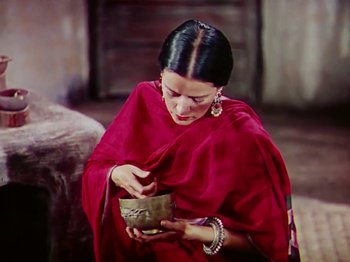 Movie still from “The Jungle Book” (1942), directed by Zoltan Korda – A woman in a red dress is holding a bowl; Medium shot, High angle
