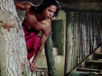 Movie still from “The Jungle Book” (1942), directed by Zoltan Korda – A shirtless man leaning on a tree trunk; Medium shot, Low angle