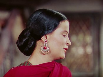 Movie still from “The Jungle Book” (1942), directed by Zoltan Korda – A woman in a red dress with her hair in a low bun; Close Up shot, Low angle