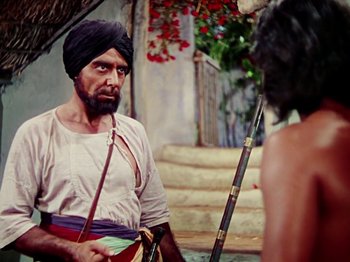 Movie still from “The Jungle Book” (1942), directed by Zoltan Korda – A man in a turban is talking to a woman in front of stairs; Medium shot, Over the shoulder angle