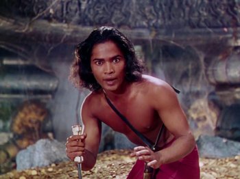 Movie still from “The Jungle Book” (1942), directed by Zoltan Korda – A shirtless man holding a sword in front of a waterfall; Medium shot, High angle