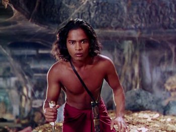 Movie still from “The Jungle Book” (1942), directed by Zoltan Korda – A shirtless man holding a sword in a cave; Medium shot, Low angle