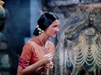 Movie still from “The Jungle Book” (1942), directed by Zoltan Korda – A woman in an orange dress is holding a candle; Medium shot, Low angle