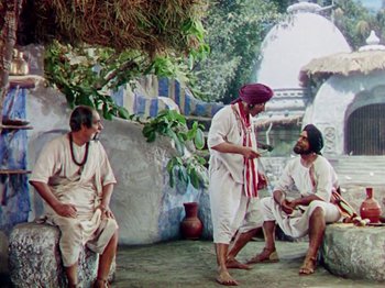 Movie still from “The Jungle Book” (1942), directed by Zoltan Korda – A group of men sitting on top of a stone wall; Wide shot, High angle