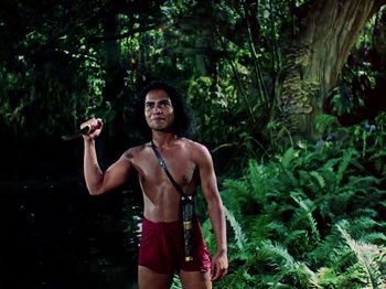 Movie still from “The Jungle Book” (1942), directed by Zoltan Korda – A man holding something in his hand while standing next to a river; Medium shot, Low angle