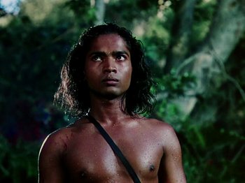 Movie still from “The Jungle Book” (1942), directed by Zoltan Korda – A man with long black hair is standing in the woods; Close Up shot, Low angle