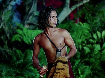 Movie still from “The Jungle Book” (1942), directed by Zoltan Korda – A man with long black hair holding a spear; Medium shot, Low angle