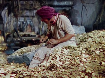 Movie still from “The Jungle Book” (1942), directed by Zoltan Korda – A man sitting on a pile of wood shavings; Wide shot, High angle