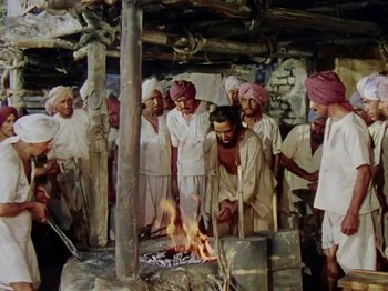 Movie still from “The Jungle Book” (1942), directed by Zoltan Korda – A group of men standing around a fire; Wide shot, High angle