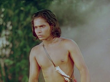 Movie still from “The Jungle Book” (1942), directed by Zoltan Korda – A man with long hair and a bare chest is holding a sling; Medium shot, Low angle
